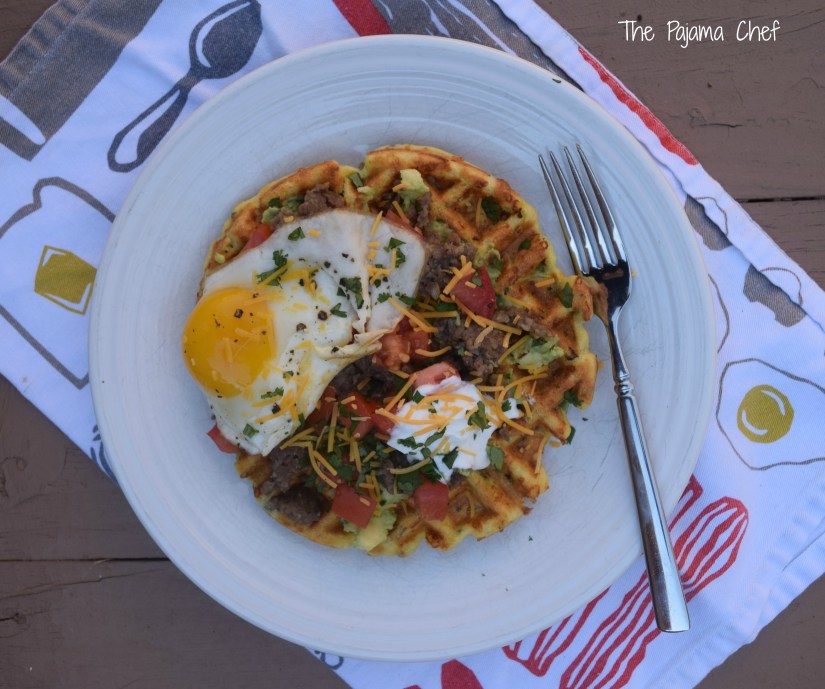 Cornbread waffles filled with cheese, peppers, and onions are loaded with sausage, tomatoes, a creamy avocado spread, and a fried egg for an impressive brunch like no other! This is a fantastic restaurant-worthy dish that's easy to make at home. You'll be sure to love it! #secretrecipeclub